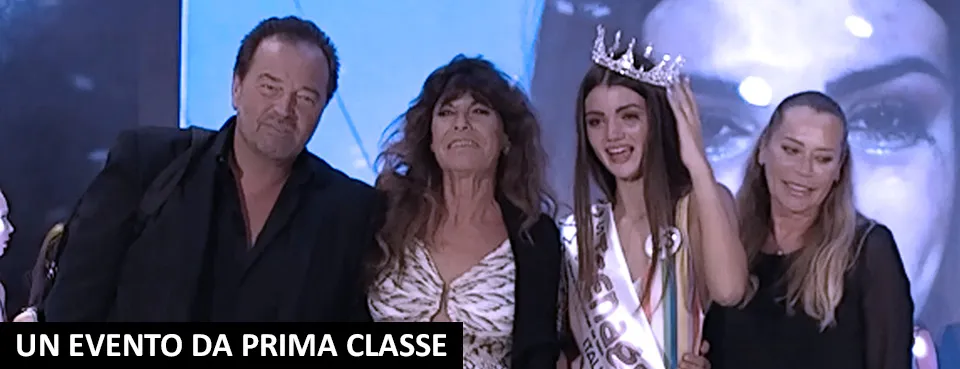 Sul palco di Miss Teenager Original 2019, una concorrente con corona e fascia insieme ad altre tre persone