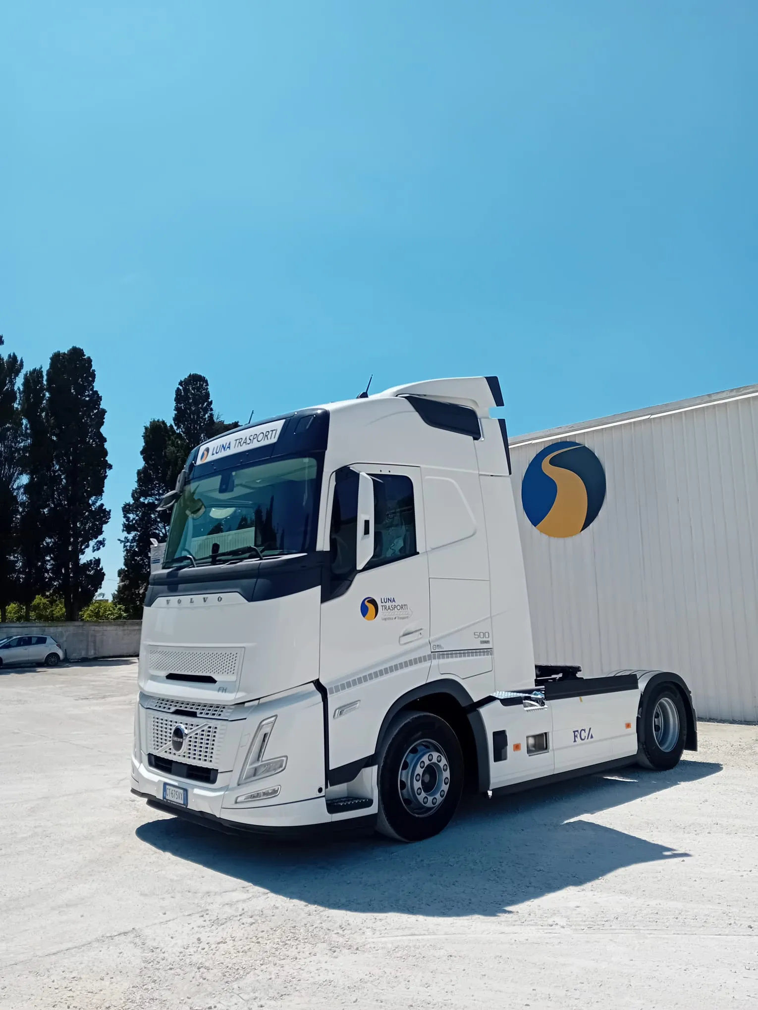 Il Volvo FH 500 visto di tre quarti anteriori davanti al capannone con il logo Luna Trasporti